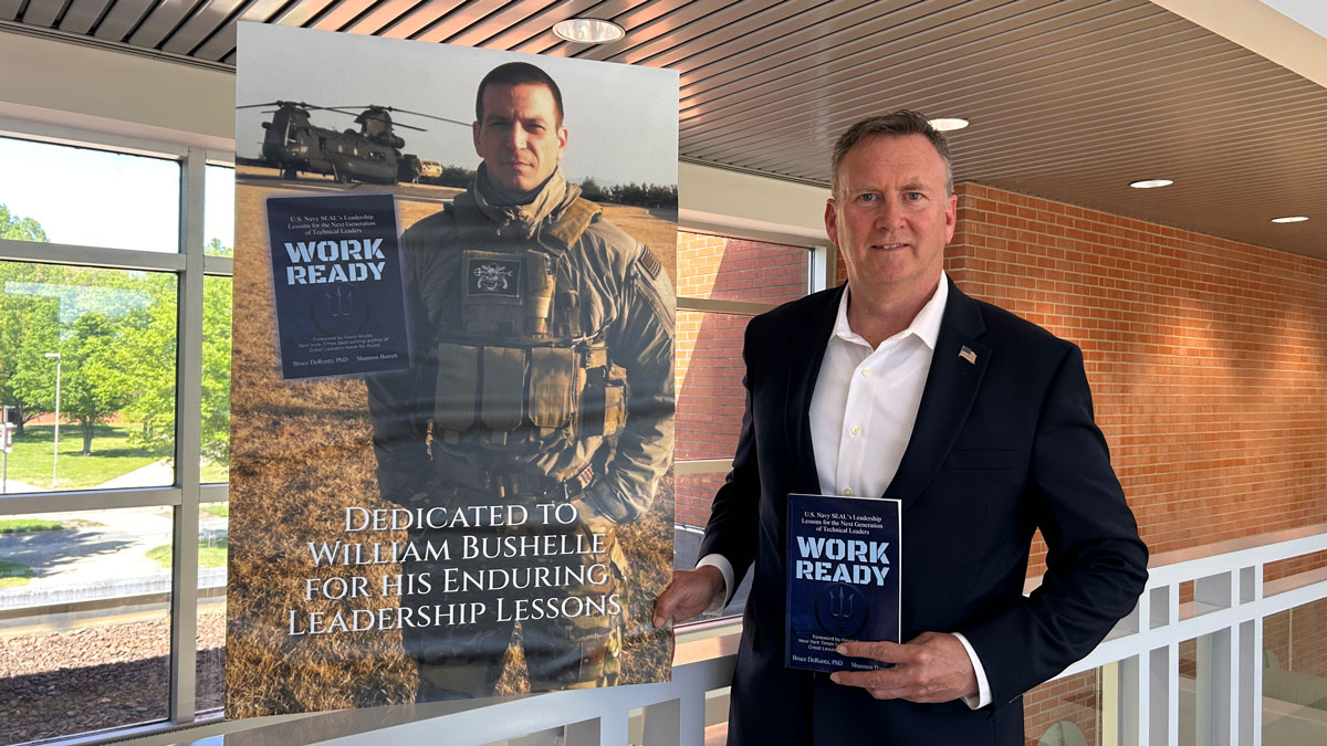 Bruce DeRuntz holding a book he co-authored called Work Ready, dedicated to William Bushelle for his enduring leadership lessons.