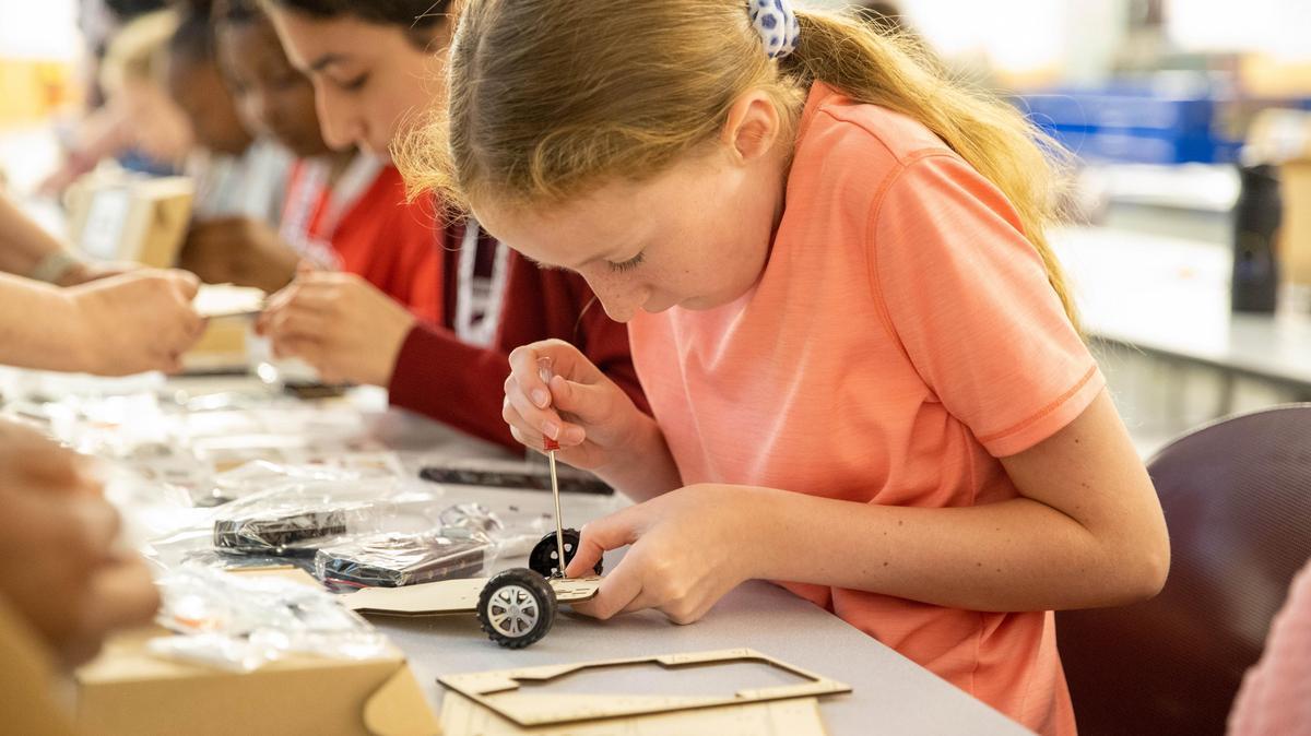 A camp participant assembles a small electronic car.