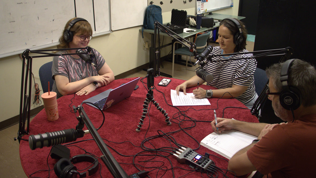 People seated around a table while doing a podcast.