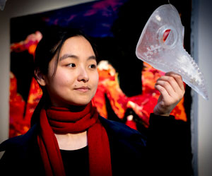 Nancy Yu holding a glass mask.