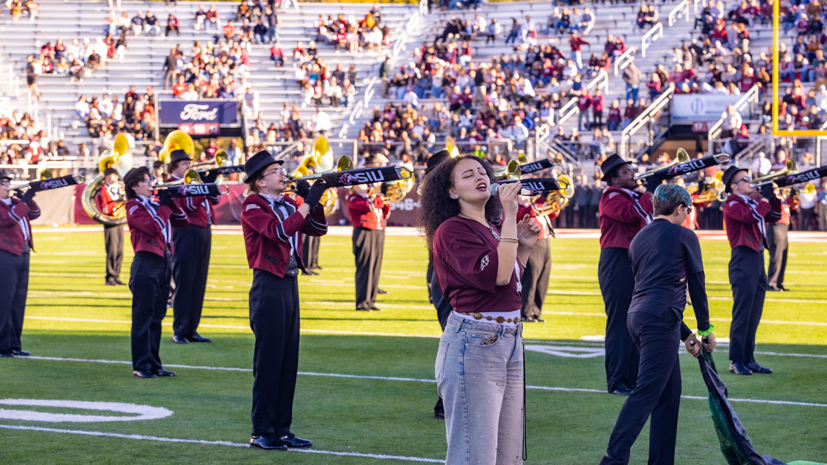 A singer now joins the ranks of the Marching Salukis, seen here at Saluki Stadium.