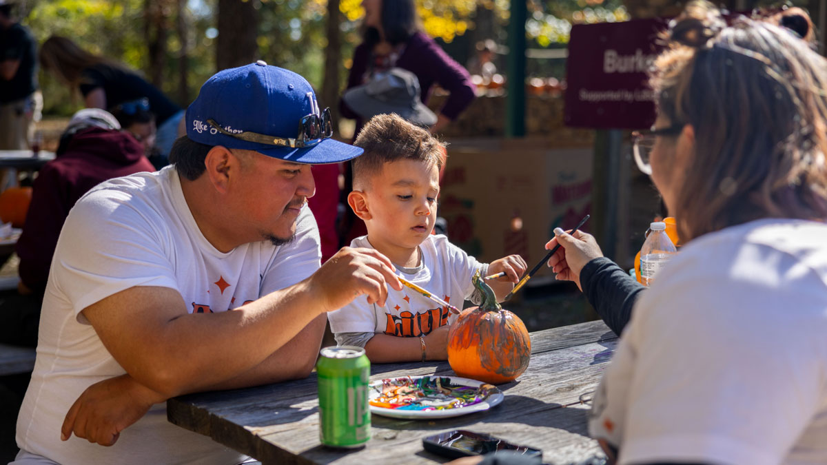 A family is painting a pumpkin.